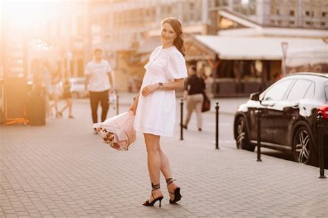 Una Mujer Feliz Con Un Vestido Blanco Al Atardecer Con Un Ramo De