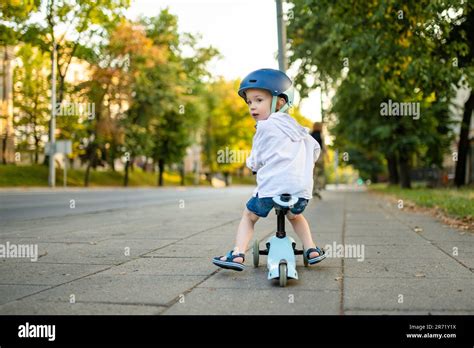 Funny toddler boy riding a baby scooter outdoors on summer day. Kid ...