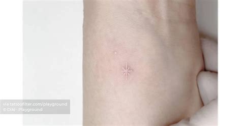 Minimalistic white star tattoo located on the wrist.