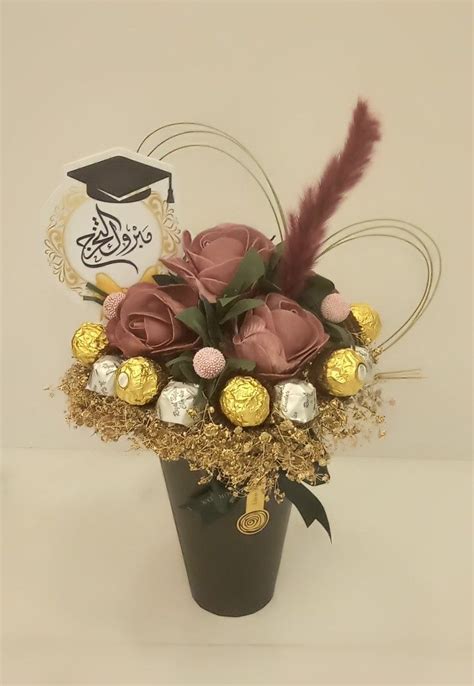 A Vase Filled With Chocolates And Flowers On Top Of A Table