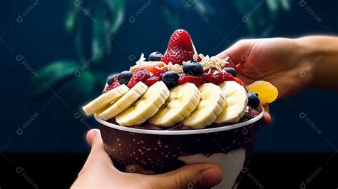 Mãos de pessoa segurando copo de açaí sobre uma sorveteria download