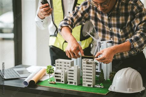 Two men engineer housing team meeting, one in safety vest holding color ...