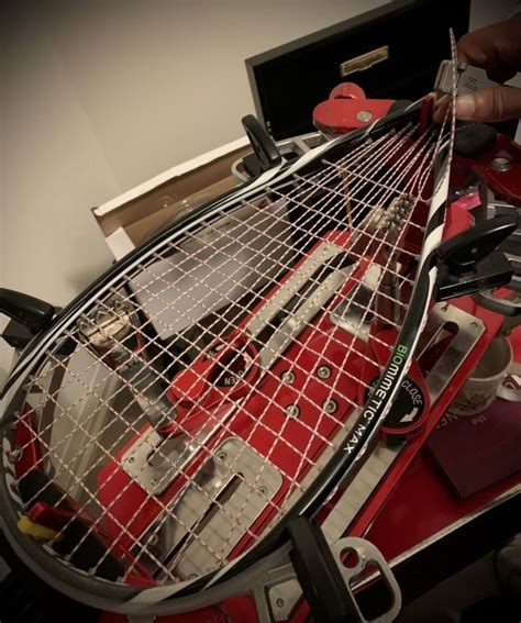 a tennis racket is being worked on by a person with scissors and pliers