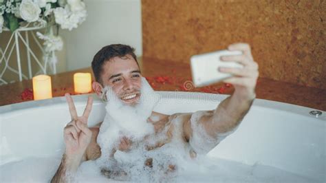 Handsome Guy Is Taking Selfie In Bathtub With Soap Foam On His Beard Using Smart Phone He Is