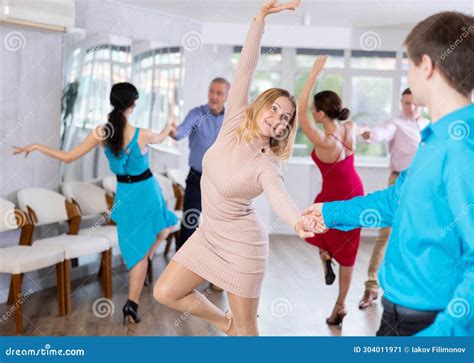 Positive Men And Women In Party Clothes Enjoying Jive In Dance Studio