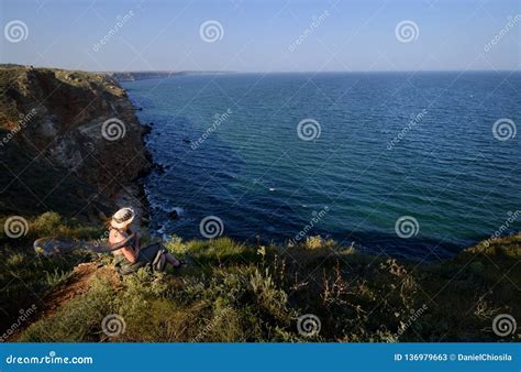 Young Woman With Hat Looking Over The Sea From A High Cliff Stock Image