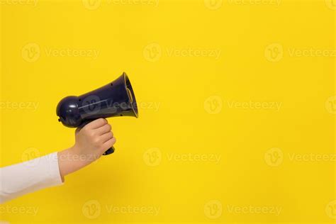 Childrens Hand Holding A Megaphone On A Yellow Background With Copy