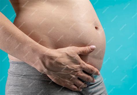 Premium Photo Pregnant Woman Holds Hands On Belly On A Blue Background