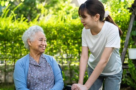 El cuidador ayuda y cuida a una anciana asiática que usa un andador con