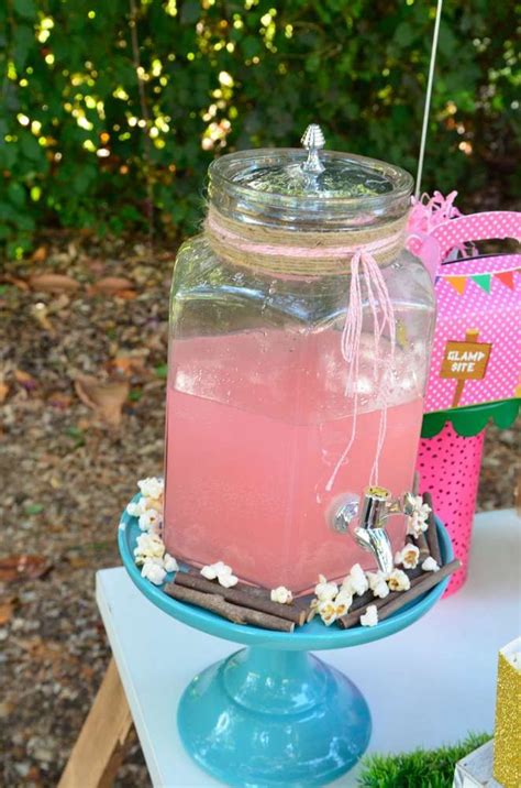 A Jar Filled With Pink Liquid Sitting On Top Of A Table Next To A Cake