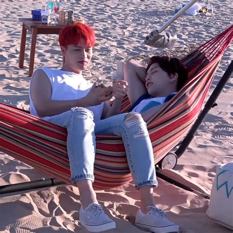 Two People Sitting In A Hammock On The Beach One With Red Hair