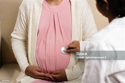 Close Up Shoulder Shot Of Doctor Examining Pregnant Woman Belly Using