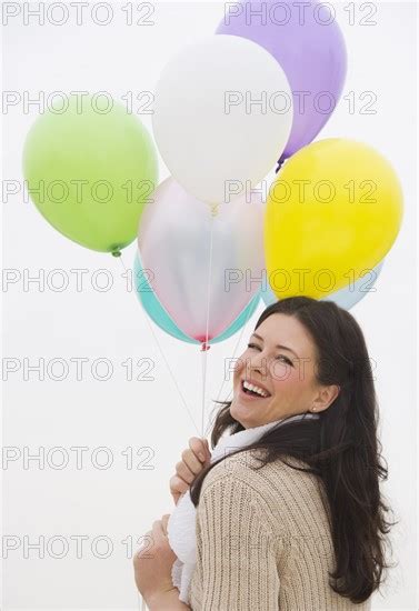 Young Woman Holding Bunch Of Balloons Laughing Photo12 Tetra Images