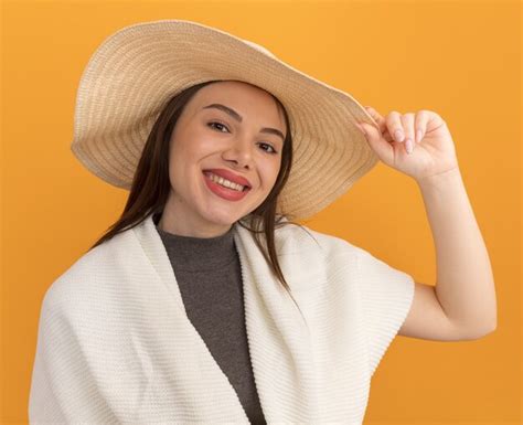 Souriante Jeune Jolie Femme Portant Et Saisissant Un Chapeau De Plage