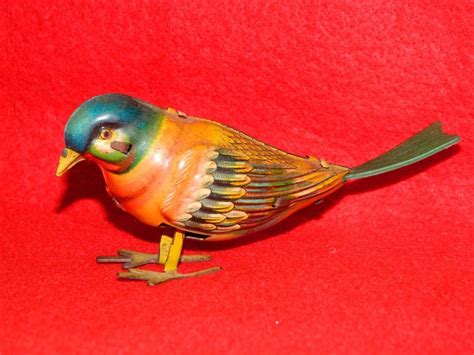 A Colorful Bird Figurine Sitting On Top Of A Red Surface With Green And