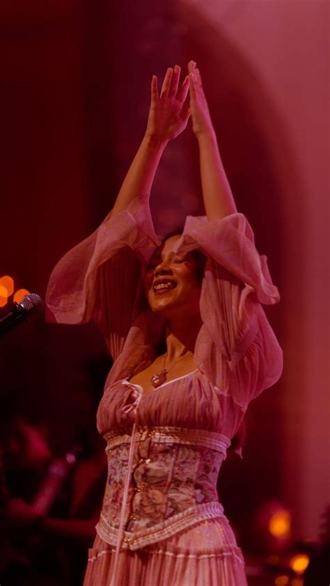 A Woman In A Pink Dress Is Holding Her Hands Up To The Air While