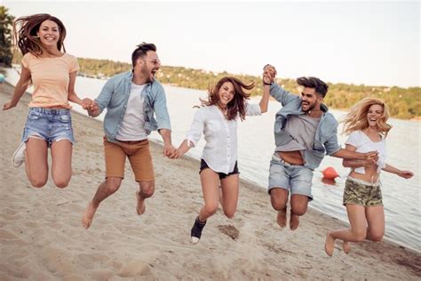 Grupo de jóvenes felices saltando en la playa Foto Premium