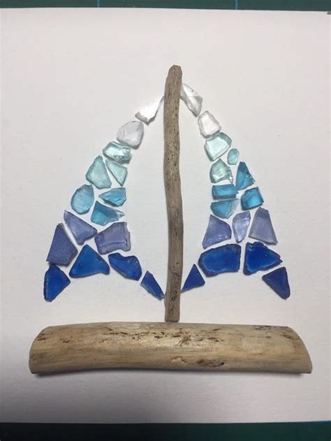 A Piece Of Art Made Out Of Sea Glass And Driftwood On A White Background