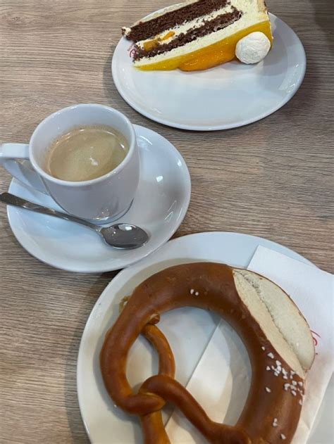 Two White Plates Topped With Desserts And Pretzels Next To A Cup Of Coffee