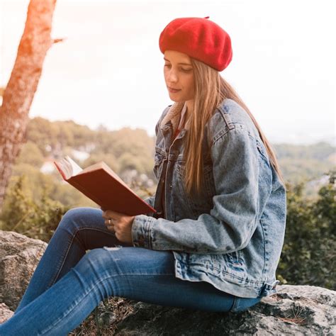 Jeune Femme Assise Sur Un Livre De Lecture Rock Photo Gratuite