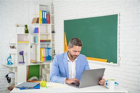 Profesor De Escuela Alegre En El Aula Con Computadora En La Pizarra