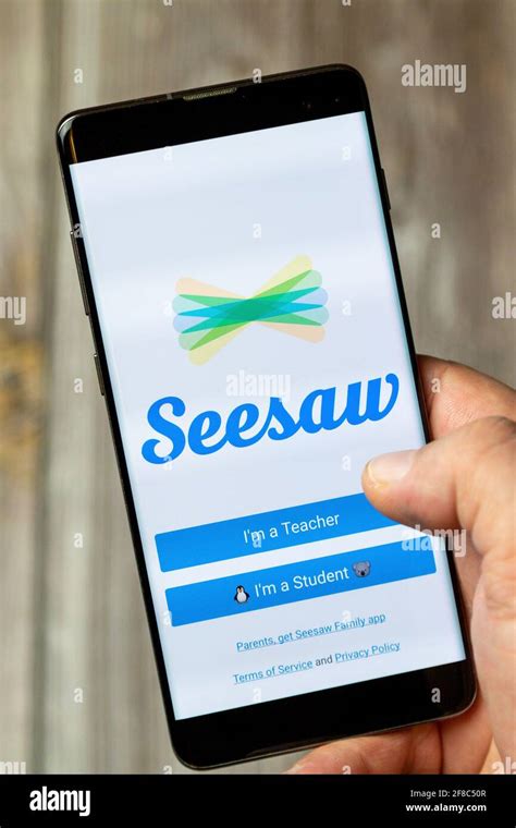 A Mobile Phone Or Cell Phone Being Held By A Hand With The Seesaw App