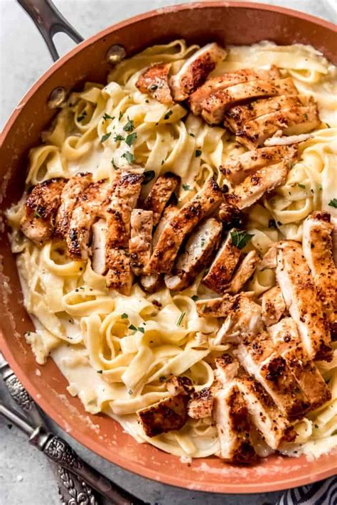 A Bowl Filled With Chicken And Pasta On Top Of A Table Next To Utensils