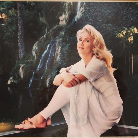 A Woman Sitting On Top Of A Fence Next To A Waterfall