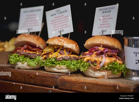 Three Beef Burgers With Cheese Bacon Lettuce Onions And Pickles On