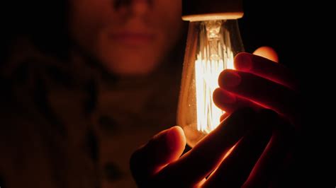 Premium Stock Video Sad Man Warms His Hands Near A Light Bulb In The Dark