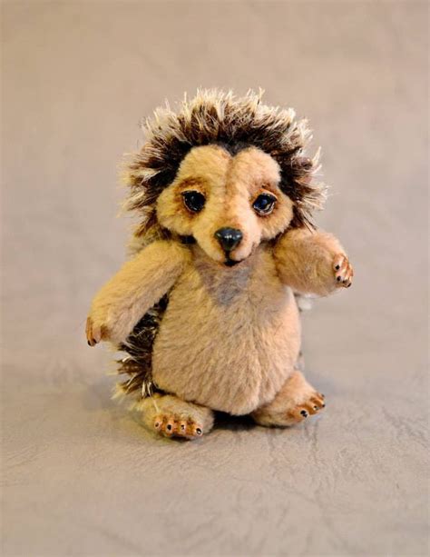 A Small Toy Hedgehog Sitting On Top Of A White Surface With Its Paws In The Air