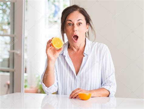 Mujer De Mediana Edad Sosteniendo Fruta Naranja Asustada En Shock Con