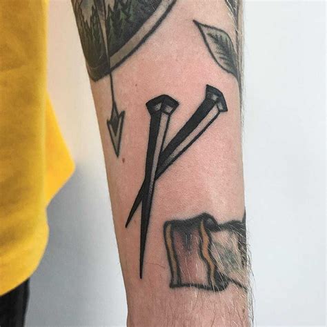 Old school style nails tattoo on the left forearm by Łukasz Krupiński