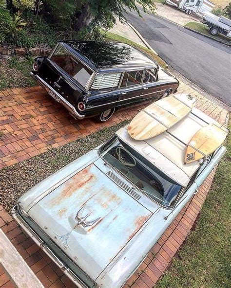 Two Old Cars Parked Next To Each Other On The Side Of A Road With