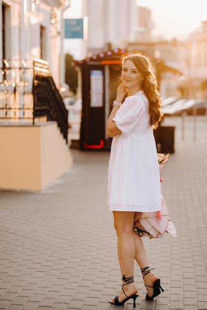 Una Mujer Feliz Con Un Vestido Blanco Al Atardecer Con Un Ramo De