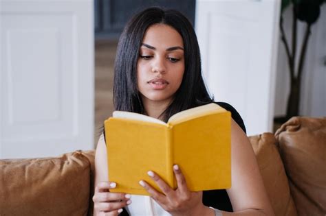 Una Joven Afroamericana Pensativa Sentada En Un Sof De Cuero Leyendo