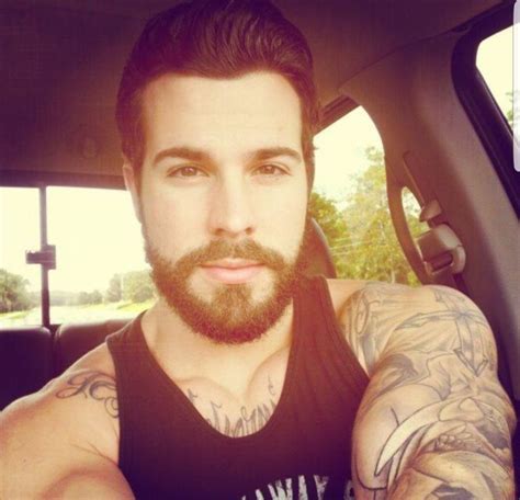 A Man With Tattoos Sitting In The Back Seat Of A Car Looking At The Camera