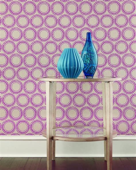 two blue vases sit on a table in front of a purple wall with circles