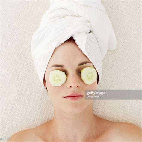 Young Woman Lying With Cucumber Slices On Eyes And Wearing Towel On