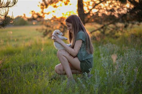 Girl Holding A Labrador Puppy And Smiling At Sunset On A Forest Glade