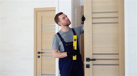 Male carpenter installing interior wood door with level in wooden