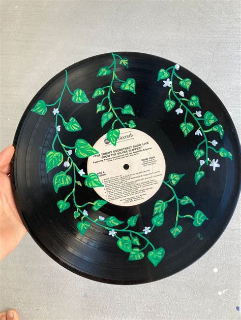 a hand holding a black record with green leaves on it