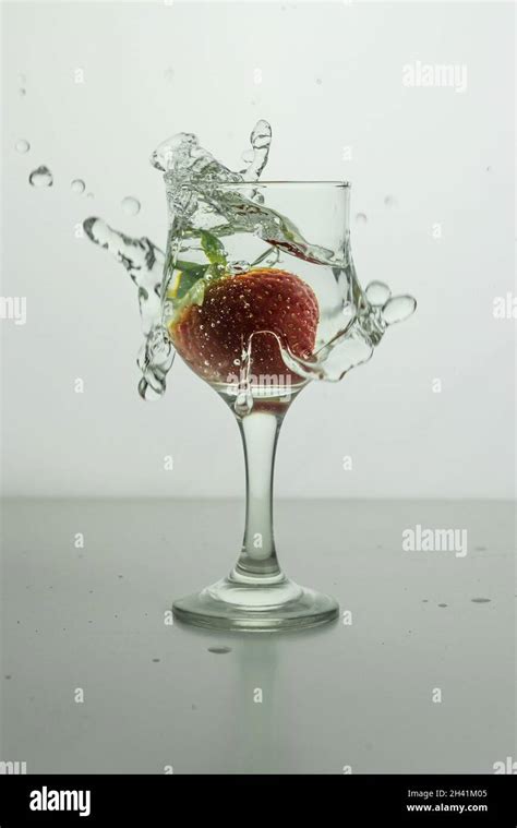 A Strawberry Dropped Into A Glass Of Waterdrinks With Splashed Fruit