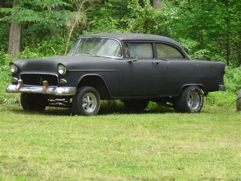 an old black car is parked in the grass