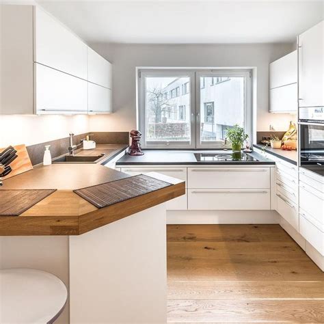 A Kitchen With White Cabinets And Wooden Counter Tops Next To An Open