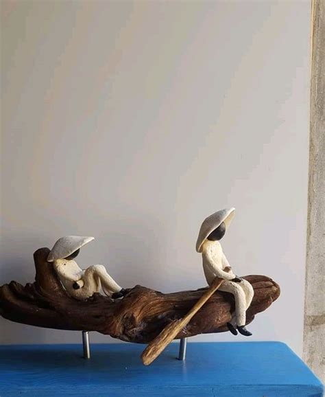 Two Figurines Are Sitting On A Piece Of Driftwood