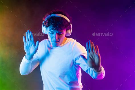 Positive Man Listening Music With Headphones Dancing On Dark Neon