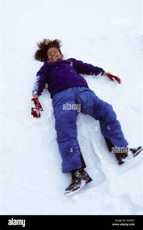 High angle view of a girl lying down in snow making a snow angel Stock ...