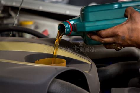 Car Mechanic Replacing And Pouring Fresh Oil Into Engine At Maintenance