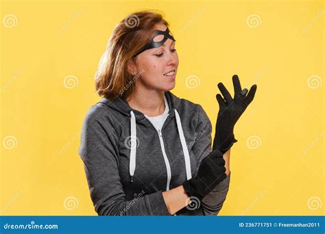 A Female Robber In A Mask Wearing Gloves Yellow Background Stock